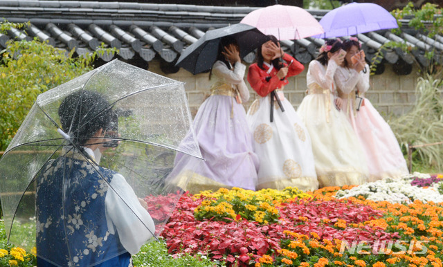 【전주=뉴시스】 김얼 기자= 선선한 날씨와 더불어 가을비가 내린 10월 7일 전북 전주시 전주한옥마을에서 관광객들이 우산으로 비를 피하며 사진을 찍고 있다. 2019.10.07.pmkeul@newsis.com