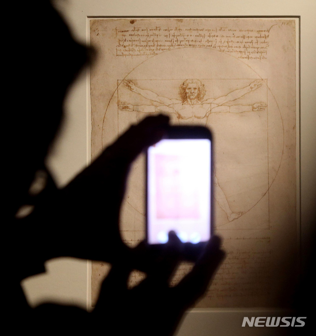 【로마=AP/뉴시스】 이탈리아 베니스 법원이 16일(현지시간) 현지 문화유산 보호단체 '이탈리아 노스트라'가 제기한 '비트루비안 맨'의 대여 금지 소송을 기각했다 관람객이 2015년 4월14일 밀라노에서 열린 한 전시에 선보인 르네상스 거장 레오나르도 다빈치의 명작 '비트루비안 맨'을 휴대폰으로 촬영하고 있다. 2019.10.17.