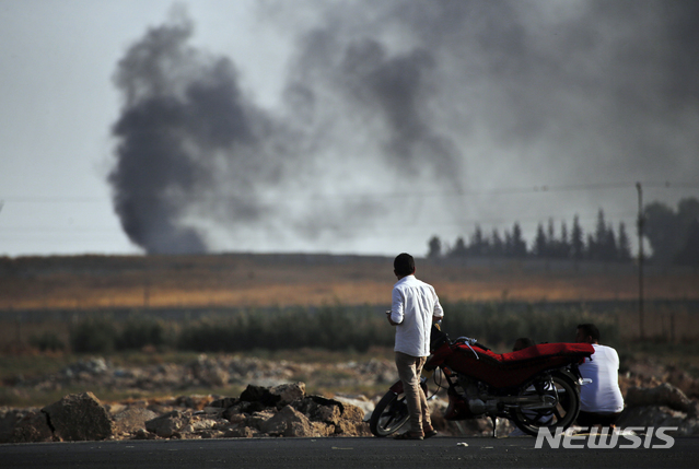 【산르우르파(터키)=AP/뉴시스】시리아와 국경을 맞댄 터키 산르우르파 지역에서 한 시민이 터키군의 폭격으로 시리아 지역에서 연기가 치솟는 것을 보고 있다. 2019.10.11 