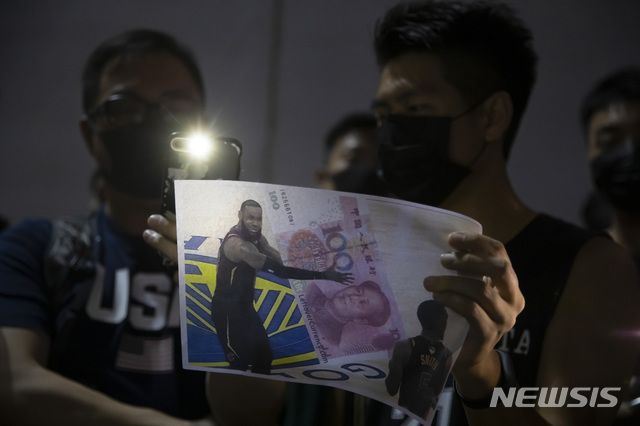 【홍콩=AP/뉴시스】15일 홍콩 완차이 지역의 서던 플레이그라운드에서 열린 시위에서 한 참가자가 미국 프로농구(NBA) 스타 르브론 제임스(LA 레이커스)가 위안화를 안고 있는 합성 사진을 들고 있다. 제임스는&nbsp; 홍콩 시위대를 옹호한 대릴 모레이 휴스턴 로키츠 단장을 지적하는 발언을 해 홍콩 시위대의 비난을 샀다. 2019.10.23.