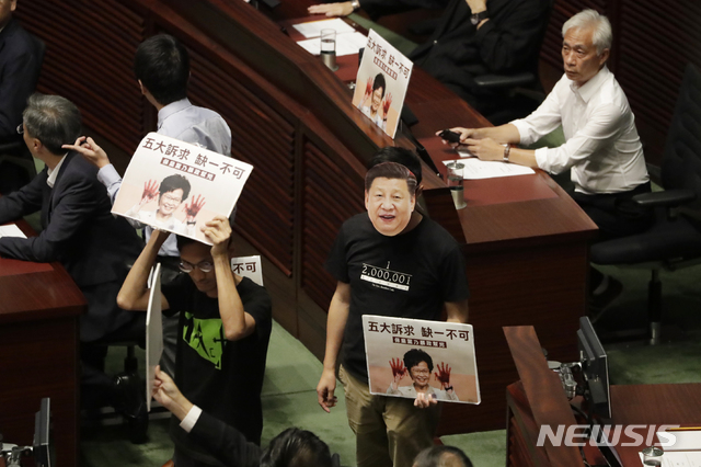 【홍콩=AP/뉴시스】16일(현지시간) 홍콩 입법회의 회의실에서 캐리 람 홍콩 행정장관의 시정연설 도중 야당 의원들이 시진핑 중국 국가주석 마스크를 쓰고 구호를 외치고 있다. 야당 의원들의 반발로 람 장관의 연설은 중단됐으며 야당 의원들은 람 장관에게 시위대가 주장하는 5가지 요구안을 수용할 것을 주장했다. 2019.10.16.