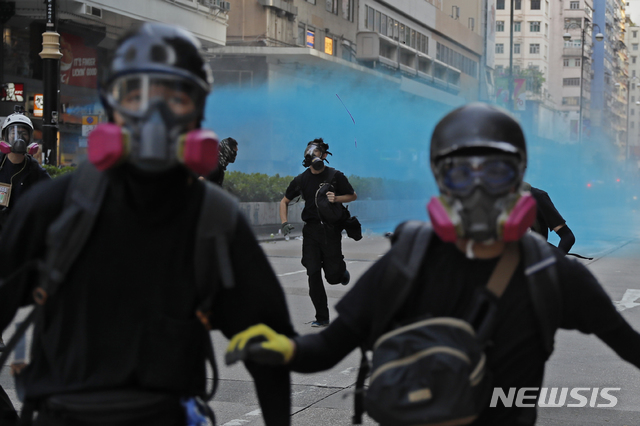 【홍콩=AP/뉴시스】20일 홍콩 도심에서 방독면을 쓴 시위대가 경찰이 쏜 파란색 물대포를 피해 도망가고 있다. 경찰은 물대포로 쏘는 물에 파란색 염료와 최루액을 섞어 시위대와 현장 취재 기자 등에 무차별적으로 발사했다. 염료는 이에 맞은 시위대를 식별하기 위한 것으로 알려졌다. 2019.10.21