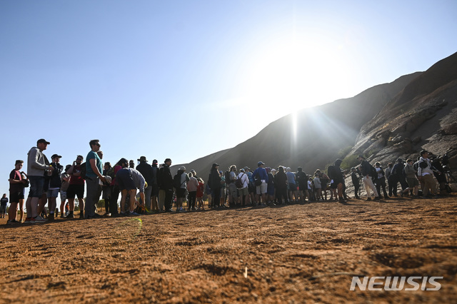 【울룰루=AP/뉴시스】등반 금지 조치가 시행되기 하루 전인 25일 호주 노던 준주 울룰루-카타튜타 국립공원에 있는 울룰루에 오르기 위해 관광객들이 긴 줄을 서 있다. 울룰루는 오는 26일부터 영구적으로 등반이 금지된다. 2019.10.25.