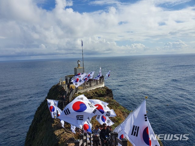 【독도=뉴시스】오동현 기자 = 10월 25일 독도의 날을 맞아 인플루언서산업협회가 '인플루언서 독도 원정대'를 꾸려 울릉군 독도를 방문했다. 이날 독도에 입도한 인플루언서산업협회와 대한민국특수임무유공자회원들이 태극기 퍼포먼스를 펼쳤다. 2019.10.25 odong85@newsis.com