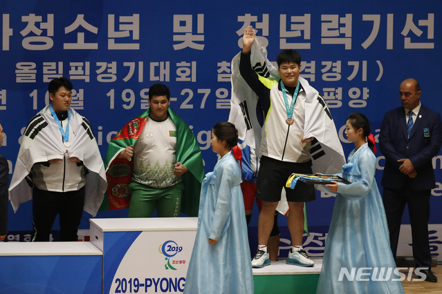 【평양=뉴시스】 사진공동취재단 = 2019 아시아 유소년·주니어 역도선수권 대회가 열리고 있는 평양 청춘가역도전용경기장에서 27일 오후 유소년 남자 +102㎏급에 출전해 용상 동메달을 획득한 이승훈(서울체고)이 시상대에 올라 손흔들고 있다.2019.10.27. photo@newsis.com
