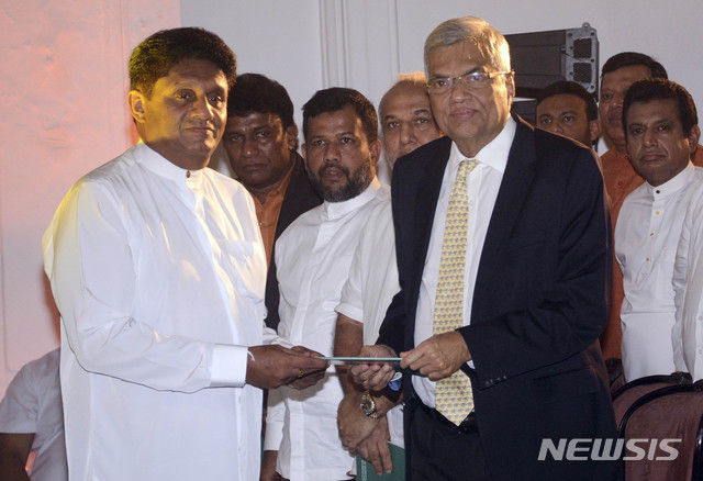 【AP/뉴시스】스리랑카 의회 다수당 후보로 16일 대선에 출마하는 사지스 프레마다사 주택장관이 1일 당수인 라닐 위크레메싱게 총리에게 공약집을 전달하고 있다. 시리세나 대통령과 위크레메싱게 총리는 지난 대선 때 연합해 마힌다 라자팍사 대통령을 물리쳤으나 이후 당 세력이 약한 시리세나 대통령과 의회를 장악한 위크레메싱게 총리 간에 갈등이 커져 심각한 정국 혼란이 초래되었다. 2019. 11. 15. 