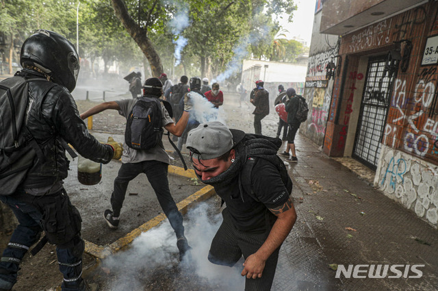 【산티아고=AP/뉴시스】11일(현지시간) 칠레 반정부 시위대가 수도 산티아고에서 시위 도중 경찰과 충돌하고 있다. 앞선 10일 곤살로 블루멜 칠레 내무장관은 정부가 아우구스토 피노체트 군부독재 시절 제정된 헌법을 개정하는 작업에 착수하기로 했다고 밝혔다. 피노체트 시절 헌법을 뜯어고치는 것은 칠레 시위대의 요구사항 중 하나였다. 2019.11.12.