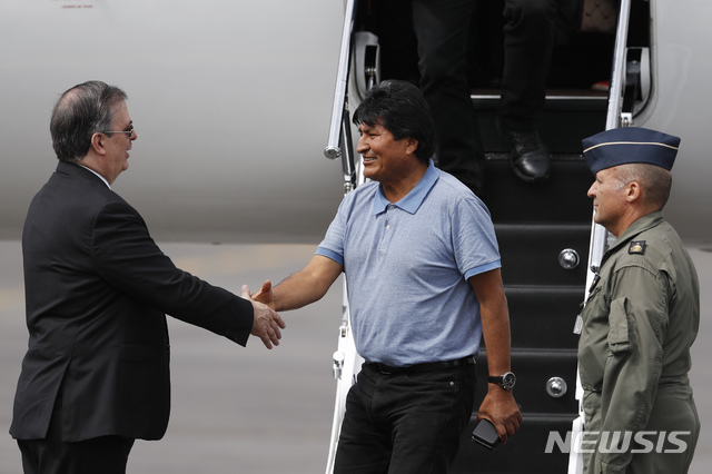 【멕시코시티=AP/뉴시스】에보 모랄레스 전 볼리비아 대통령이 12일(현지시간) 멕시코시티에 도착, 비행기에서 내리면서 마중나온 마르셀로 에브라르드 멕시코 외무장관과 악수하고 있다. 2019.11.13
