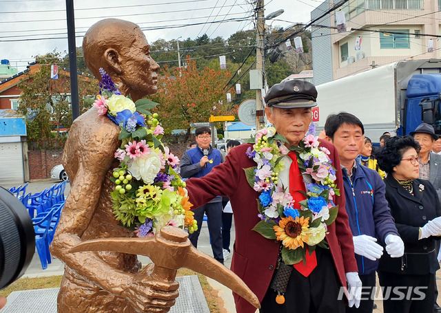 징용 피해자 박정규(95)옹이 노동자상에 꽃목걸이를 걸어주고 있다. 