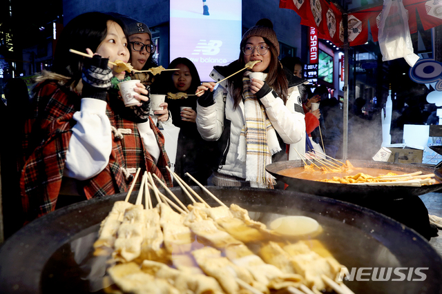 【서울=뉴시스】김병문 기자 = 외국인 관광객들이 13일 오후 서울 중구 명동거리에서 어묵을 먹으며 추위를 피하고 있다. 2019.11.13. dadazon@newsis.com