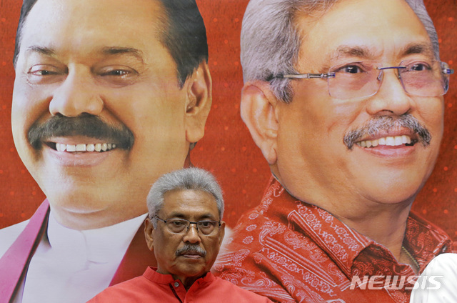 【콜롬보=AP/뉴시스】 16일 대통령선거가 치러지는 스리랑카의 수도 콜롬보에서 6일 유력한 후보인 고타바야 라자팍사 전국방장관이 자신과 형인 마힌다 라자팍사 전대통령을 나란히 등장시킨 선전판 앞에 앉아 있다. 2019. 11. 15. 