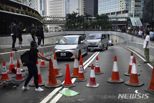  【홍콩=AP/뉴시스】14일(현지시간) 홍콩 금융가에서 시위 학생들이 도로교통용 고깔로 도로를 봉쇄하고 있다. 시위대가 주요 도로와 철도망을 폐쇄하고 파괴하면서 나흘째 도시 기능이 마비되고 있으며 유치원을 비롯한 모든 공립학교에 휴교령이 내려졌다. 대학들은 시위대의 기지로 이용되고 경찰과의 충돌로 전쟁터를 방불케 하자 휴교에 들어가 유학생들이 홍콩 '탈출'을 서두르고 있다. 2019.11.14. 