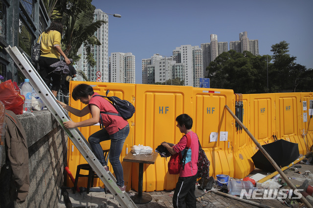 【홍콩=AP/뉴시스】15일(현지시간) 시위대가 홍콩 침례대학 인근 도로를 바리케이드로 도로를 막아 놓아 시민들이 사다리를 이용해 바리케이드를 넘어가고 있다. 시위가 격화하면서 홍콩 정부가 24일 예정인 지방의원 선거를 연기하고 야간 통행 금지령을 내릴 수 있다는 언론 보도가 잇따르는 가운데 시위대는 자신들이 막고 있던 도로를 일부 비우고 지방 선거를 예정대로 치를 것을 요구하고 있다. 2019.11.15.&nbsp;&nbsp; 