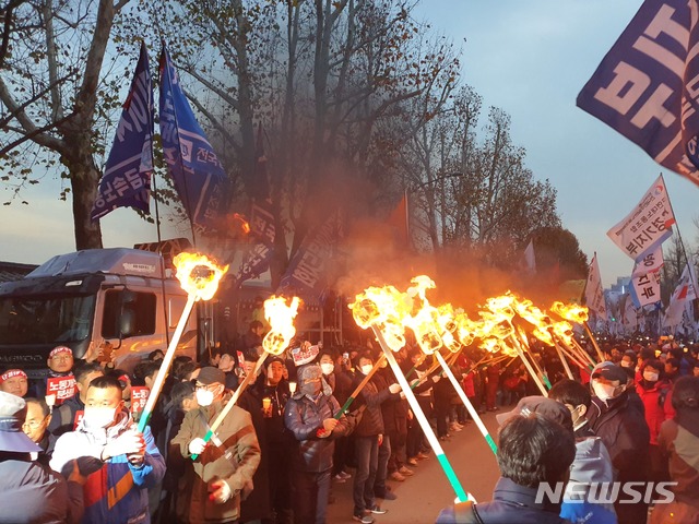 [서울=뉴시스]김정현 수습기자 = 민중대회 참가자들이 서울 종로구 청와대 앞에서 횃불을 켜고 있다. 2019.11.30. ddobagi@newsis.com