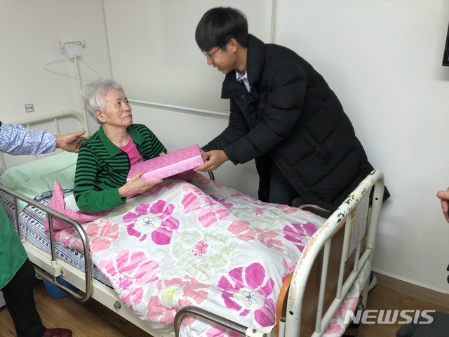 [안양=뉴시스] 박석희 기자 = 신성고등학교 학생이 병원에 입원해 있는 기초수급자를 찾아가 준비한 내복을 전달하고 있다. (사진=안양시 제공)