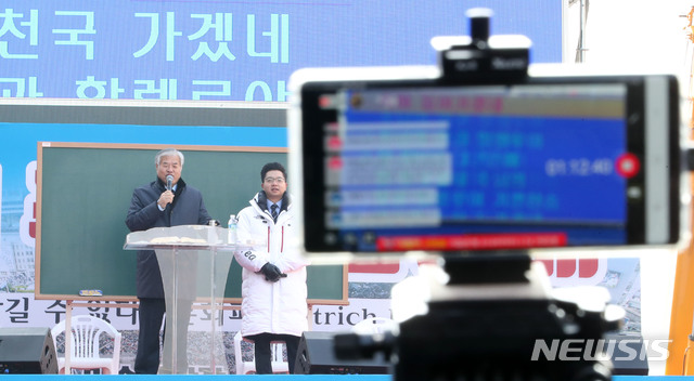 [서울=뉴시스]박미소 기자 = 8일 오전 서울 종로구 광화문 교보빌딩 앞에서 문재인하야범국민투쟁본부 주최로 열린 '대한민국 바로세우기 국민대회'에서 전광훈(왼쪽) 목사가 설교하는 모습을 한 유투버가 생중계하고 있다. 2019.12.08. misocamera@newsis.com