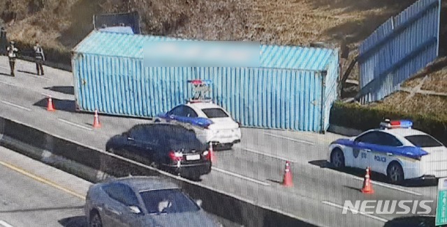 [부산=뉴시스] 12일 낮 12시 5분께 부산 해운대구 장산터널 인근 도로에서 운행 중이던 트레일러 차량에 실려 있던 컨테이너가 도로로 넘어졌다. (사진=부산경찰청 제공). 2019.12.12.photo@newsis.com 