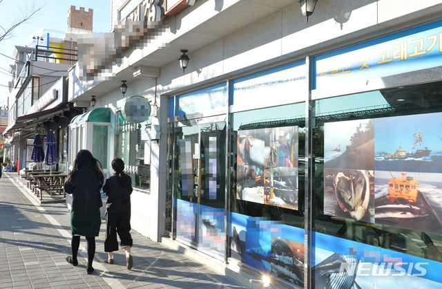 [울산=뉴시스]배병수 기자 = 30일 울산 남구 장생포에서 영업 중인 한 고래고기 전문점 앞으로 시민들이 지나가고 있다. 2019.12.30. bbs@newsis.com