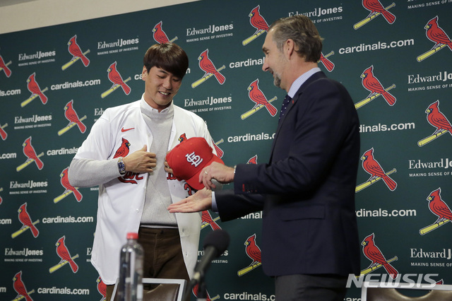 [세인트루이스=AP/뉴시스]김광현이 17일(현지시간) 미 미주리주 세인트루이스에서 열린 입단 기자회견장에서 카디널스 유니폼을 입고 존 모젤리악&nbsp; 단장으로부터 모자를 건네받고 있다. 좌완 김광현은 2년, 800만 달러 계약에 입단했으며 등 번호는 33번으로 알려졌다. 2019.12.18.