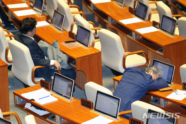 [서울=뉴시스] 고승민 기자 = 24일 오전 서울 여의도 국회에서 예산부수법안과 공수처법, 유아교육법 개정안 등을 안건으로 열린 본회의에서 권성동 자유한국당 의원이 필리버스터를 하는 동안 밤을 지새운 민주당 의원들이 지친 모습을 보이고 있다. 2019.12.24.kkssmm99@newsis.com