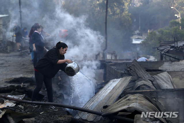 [발파라이소( 칠레 )= AP/뉴시스] 칠레 발파라이소 시외에서 12월 25일( 현지시간) 산불로 불 탄 집터에 물을 퍼붓고 있는 주민들.&nbsp;&nbsp;&nbsp;&nbsp;&nbsp; 