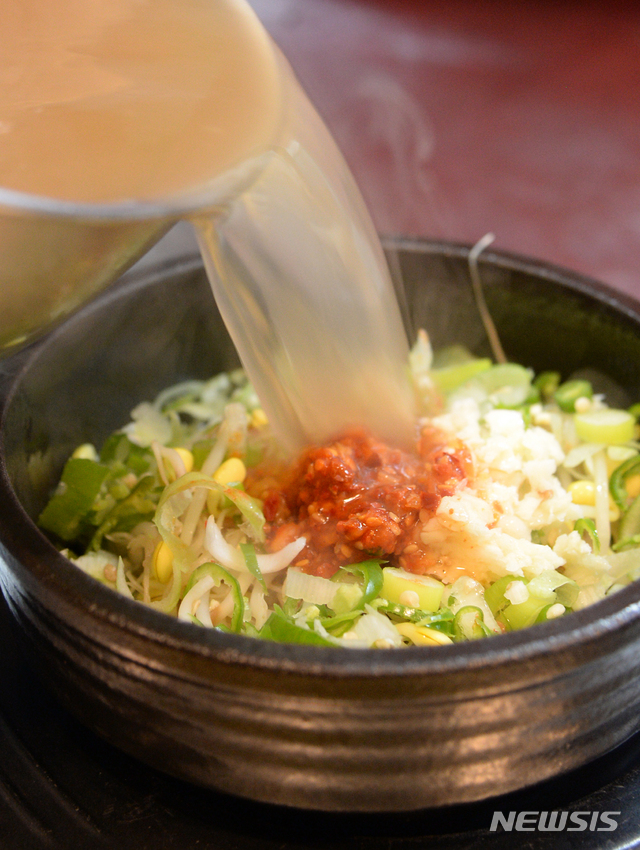 [전주=뉴시스] 김얼 기자= 23일 전북 전주시 현대옥 전주본점(전주중화산점)에서 직원이 토렴을 마친 콩나물 국밥에 국물을 넣고 있다. 2019.12.23. pmkeul@newsis.com