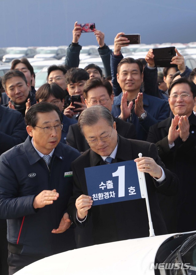 [평택=뉴시스]배훈식 기자 = 문재인 대통령이 3일 평택항에서 2020년 친환경차 수출 1호 '니로'에 기념 깃발을 달아주고 있다. 2020.01.03. dahora83@newsis.com