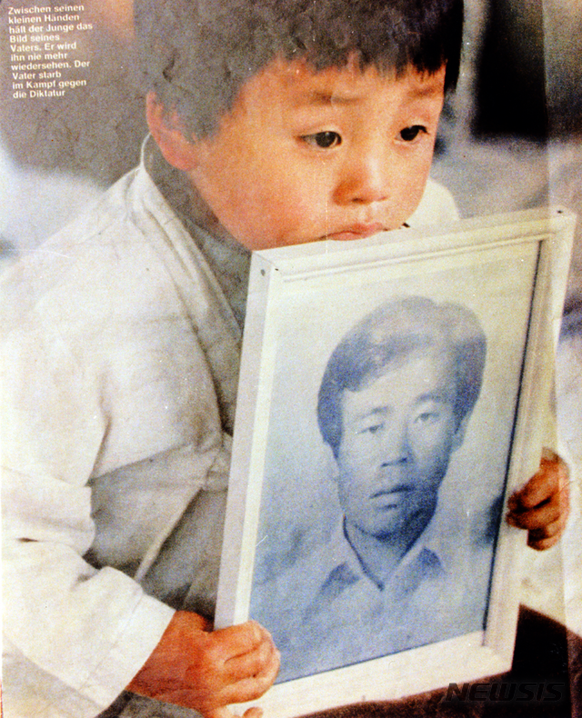 [광주=뉴시스]변재훈 기자 = 1980년 5·18민주화운동 과정 중 광주 금남로에서 계엄군 총에 맞아 숨진 조사천 씨(당시 34세)의 영정사진을 아들 조천호 씨(당시 5세)가 들고 있는 모습. (사진=뉴시스 DB) 2020.01.05. photo@newsis.com