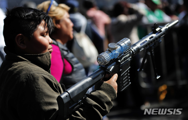 [ 멕시코시티= AP/뉴시스] 멕시코의 전통 명절인 성탄절로부터 12일째 되는 '킹스 데이' 전야에 장난감 기관총을 선물로 받고 기뻐하는 소년. 이 날은 동방박사 3명을 기념하는 축제로 아이들이 '진짜 성탄절 선물'을 받는 날이지만 멕시코시티 장난감 시장에서는 총격으로 2쌍의 부자가 죽거나 다쳤다.&nbsp; 