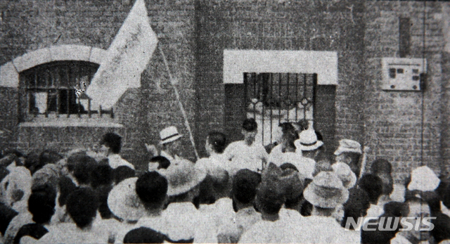 [서울=뉴시스]‘혁명동지 환영’이라고 급하게 쓴 깃발을 든 군중들이 서대문형무소 문이 열리기를 기다리고 있다. (사진=미디어한국학 제공) 2020.01.12.photo@newsis.com