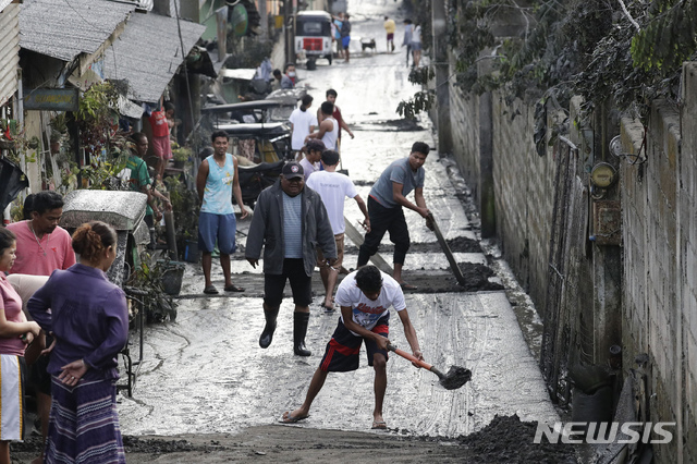  [타가이타이(필리핀)=AP/뉴시스]12일(이하 현지시간) 필리핀 수도 마닐라 남부 카비테주 타가이타이의 탈(Taal) 화산이 폭발해 13일 인근 주민들이 동네에 쌓인 화산재를 치우고 있다. 2020.01.13. 