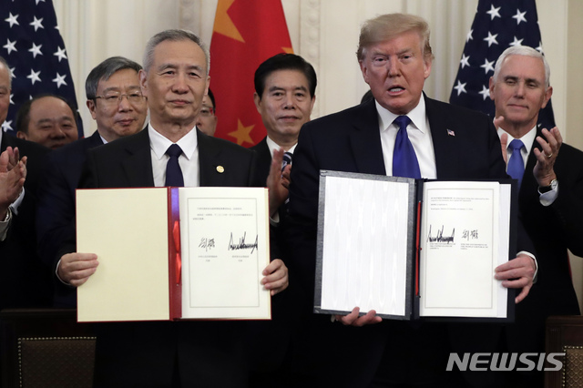 President Donald Trump signs a trade agreement with Chinese Vice Premier Liu He, in the East Room of the White House, Wednesday, Jan. 15, 2020, in Washington. (AP Photo/Evan Vucci)