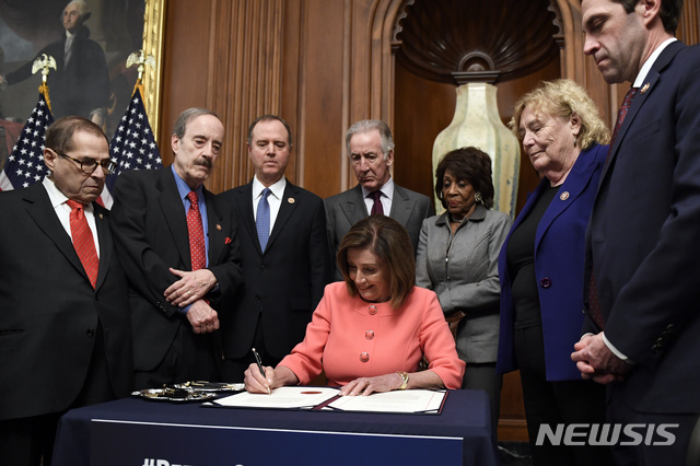 [워싱턴=AP/뉴시스]낸시 펠로시(가운데) 미 하원의장이 15일(현지시간) 워싱턴 의사당에서 탄핵소추위원 7명이 배석한 가운데 상원에 제출한 트럼프 대통령 탄핵안 상원 송부 결의안에 서명하고 있다. 2020.01.16.