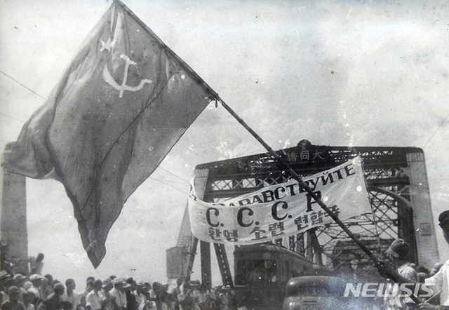 [서울=뉴시스] 1945년 8월 26일 평양에 입성한 소련 제25군을 평양 시민들이 대동교 앞에서 소련기와 ‘환영 소련 련합국’이라 쓴 현수막을 들고 환영하고 있다. (사진=미국 국립문서기록청) 2020.01.19.&nbsp;&nbsp; photo@newsis.com
