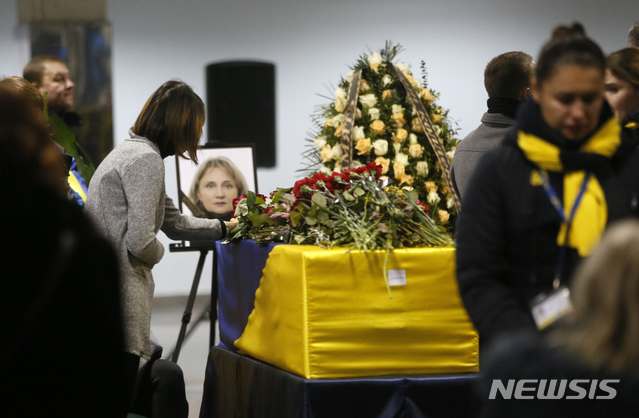 [키예프(우크라이나)=AP/뉴시스]한 여성이 19일 우크라이나 키예프 국제공항에서 열린 추모식에서 이란에서 추락한 우크라이나 여객기 승무원에게 헌화하고 있다. 여객기 블랙박스를 우크라이나로 보낼 것으로 알려졌던 이란은 이날 입장을 번복, 블랙박스를 외국으로 보내지 않을 것이라고 밝혔다. 2020.1.19