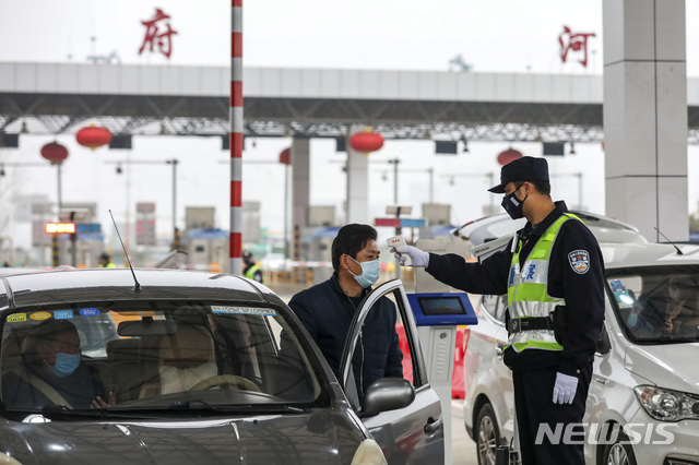 [우한=AP/뉴시스]23일(현지시간) 신종 코로나바이러스가 발발한 중국 후베이성 우한의 고속도로 톨게이트에서 경찰이 한 운전자의 체온을 검사하고 있다. 2020.01.24. 