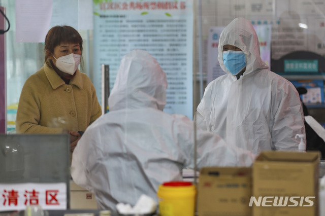 [우한=AP/뉴시스] 중국 우한의 한 보건소에서 27일 환자로 보이는 한 여성과 의료진이 나란히 서있다. 2020.01.28 