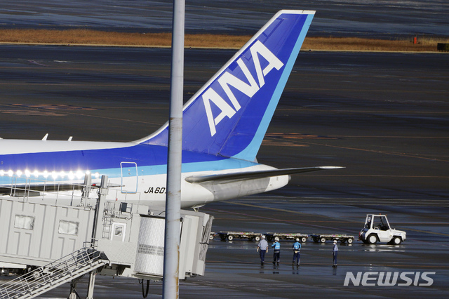 [도쿄=AP/뉴시스]중국 우한에서 자국민을 태운 전세기가 29일 일본 도쿄 하네다 국제공항에 도착해 마스크를 쓴 공항 직원들이 항공기 근처에서 대기하고 있다. 일본 정부는 중국 후베이성 우한 내 자국민 귀국 희망자 650명에 대해 전세기를 마련해 1진으로 206명이 돌아왔다. 2020.01.29.