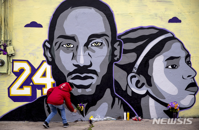 [오스틴=AP/뉴시스]30일(현지시간) 미 텍사스주 오스틴의 한 식당 뒤편 벽에 헬기 사고로 숨진 미프로농구(NBA) 전설 코비 브라이언트와 그의 딸 지안나의 벽화가 그려져 한 주민이 그 앞에 헌화하고 있다. 2020.01.31.
