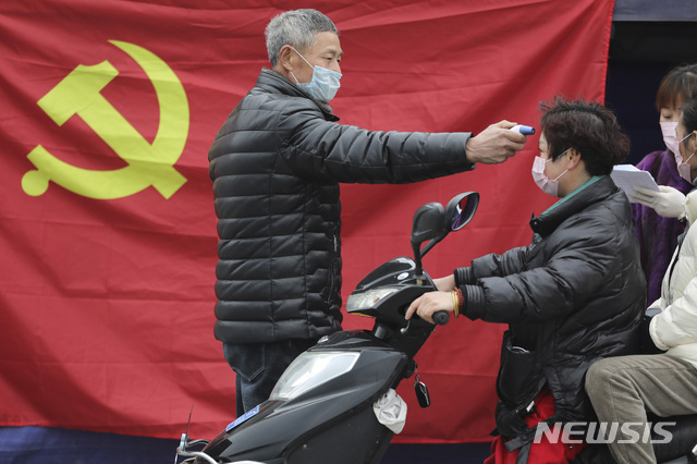 [항저우=AP/뉴시스] 중국 동부 저장성 대도시에서 3일 공산당 기 앞에서 한 자원봉사자가 도로변 검역 포인트에 온 스쿠터 운전자의 체온을 재고 있다. 현재 중국은 34개 전 성시자치구에 걸쳐 1만7000명이 넘는 신종 코로나 감염증 확진자가 나왔다. 사망자는 361명 중 11명을 제외하고 모두 후베이성 환자들이다. 2020. 2. 3.  