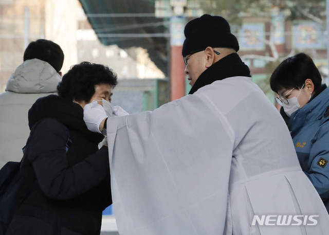 [서울=뉴시스] 최동준 기자 = 지현 조계사 주지스님이 4일 서울 종로구 조계사 일주문 앞에서 신종 코로나바이러스(우한 폐렴) 예방을 위해 신도들에게 마스크를 나누어 주고 있다. 2020.02.04. photocdj@newsis.com