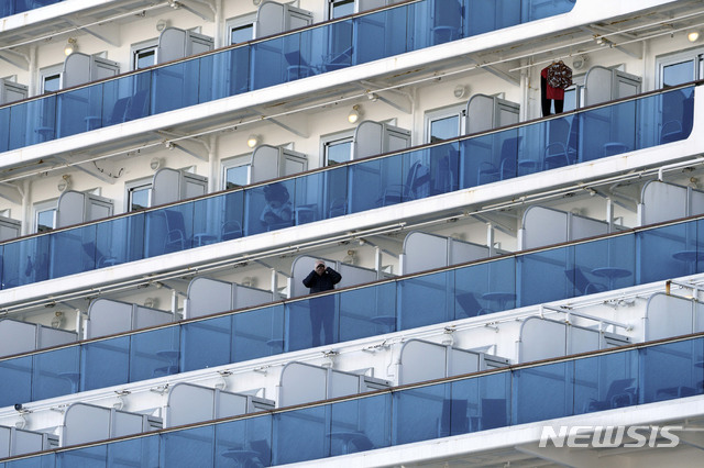 [요코하마=AP/뉴시스] 신종 코로나 바이러스 감염증 확진자가 무더기로 나온 일본 크루즈선 다이아몬드 프린세스에서 6일(현지시간) 승객이 테라스에 나와 밖을 내다보고 있다. 이 크루즈선은 현재 요코하마에 정박해있으며, 승객들은 하선을 하지 못하고 선내에 머무르고 있다. 2020. 02. 07 .&nbsp; 