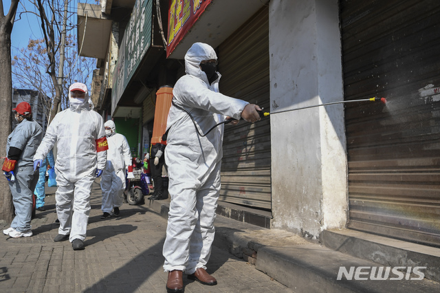 [우한=신화/뉴시스] 중국 후베이성 우한의 장안에서 10일 방역요원들이 닫힌 가게 문에 소독약을 뿌리고 있다. 2020.02.13 