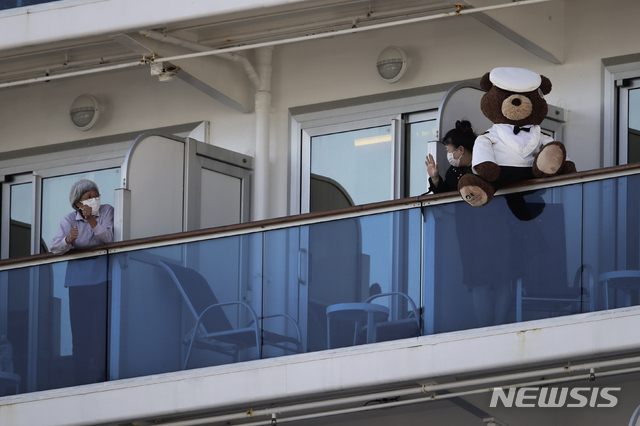 [요코하마=AP/뉴시스]11일 일본 요코하마항에 정박해 있는 유람선 '다이아몬드 프린세스'호에서 테디베어 인형을 든 한 여성이 다른 여성과 손 인사를 나누고 있다. 가토 가쓰노부 후생노동상은 전날 언론과의 인터뷰에서 유람선에 탑승한 승객과 승무원 전원에 대한 신종 코로나 검사를 고려 중이라고 밝혔다. 2020.02.11.&nbsp; 