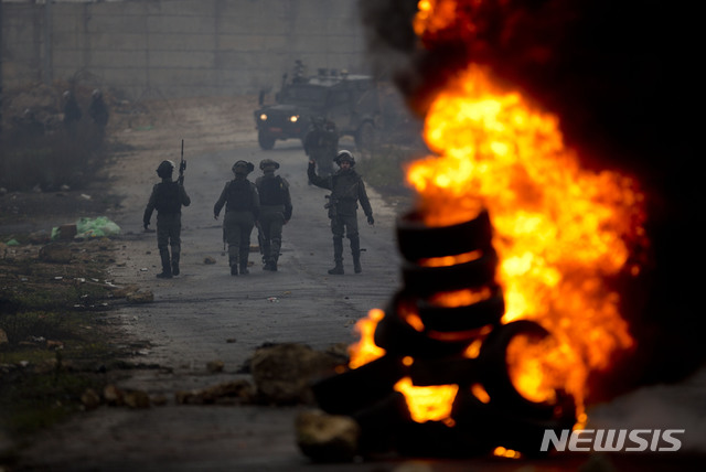 [라말라(팔레스타인)=AP/뉴시스]지난 2월11일(현지시간) 팔레스타인 라말라 서안지구에서 미국의 중동평화안에 반대하는 시위가 열려 팔레스타인 시위대와 이스라엘 군인이 불타는 타이어 더미를 사이에 두고 대치하고 있다. 2020.05.21