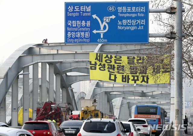 [서울=뉴시스]이윤청 기자 = 한 남성이 14일 오전 한강대교 아치 위에서 ‘세상은 달라졌다. 남성 관련 법과 제도 다 바꾸자’라는 문구가 적힌 현수막을 내걸고 농성하고 있다. 2020.02.14. radiohead@newsis.com