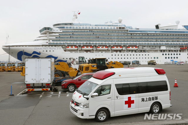 [요코하마=AP/뉴시스]신종 코로나바이러스 감염증(코로나19)이 집단 발병한 크루즈선 다이아몬드 프린세스호가 정박하고 있는 도쿄 인근 요코하마항을 14일 구급차 1대가 떠나고 있다. 2020.2.14