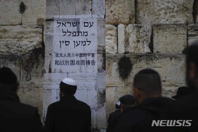 [예루살렘=AP/뉴시스] 16일(현지시간) 이스라엘 예루살렘 '통곡의 벽' 앞에서 유대인들이 기도하고 있다. 신종 코로나바이러스 감염증(코로나19)이 전세계에서 확산되는 가운데 유대교 성지인 통곡의 벽에는 "유대인은 중국의 평안과 어려움 극복을 위해 기도한다"는 내용의 포스터가 부착됐다. 2020.02.17