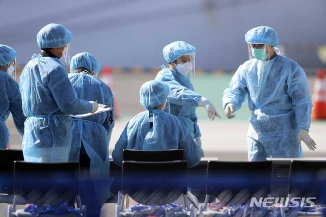 [요코하마=AP/뉴시스]방호복을 입은 관계자들이 21일 일본 요코하마항에 격리, 정박 중인 유람선 다이아몬드 프린세스호에서 하선할 승객들을 기다리고 있다. 2020.02.21. 