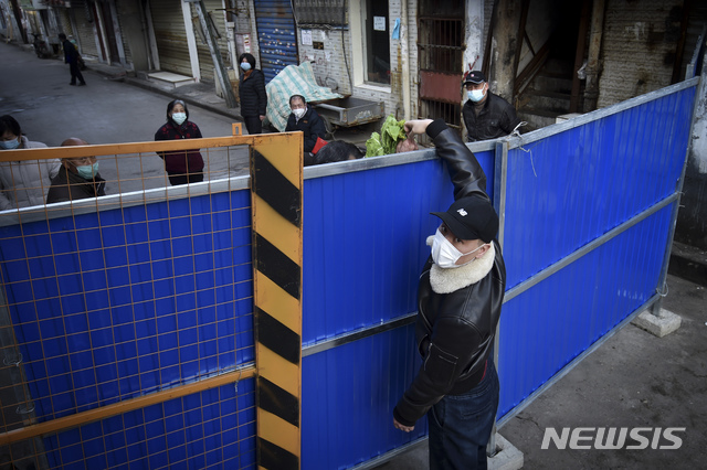 [우한=AP/뉴시스]23일(현지시간) 중국 후베이성 우한의 한 주택가에서 한 남성이 가림막 너머로 채소를 전달하고 있다. 시진핑 중국 국가주석은 23일 신종 코로나바이러스 감염증 관련 "코로나19는 전파 속도가 가장 빠르고 방역 난도는 가장 높은 돌발 공중위생 사건"이라며 "방역 업무가 조금도 느슨해져선 안 될 것"이라고 강조했다. 2020.02.24.